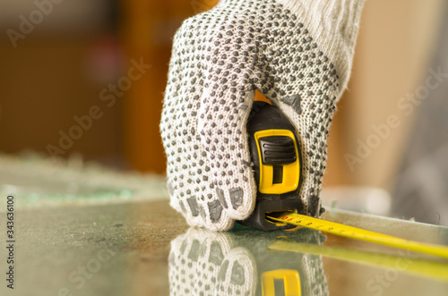 Closeup hand wearing white work gloves using measure tool on transparent piece of glass photo