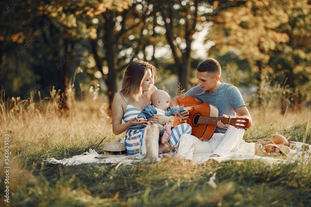 Family with cute little son. Father in a gray shirt. Family on a picnic. Man playing on a guitar