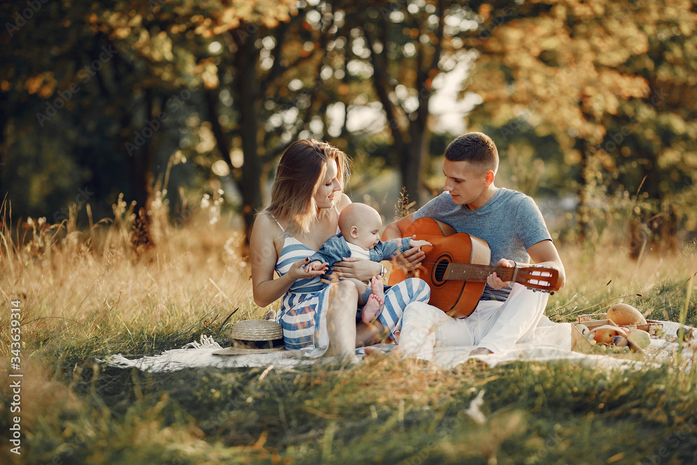 Family with cute little son. Father in a gray shirt. Family on a picnic. Man playing on a guitar Family with cute little son. Father in a gray shirt. Family on a picnic. Man playing on a guitar