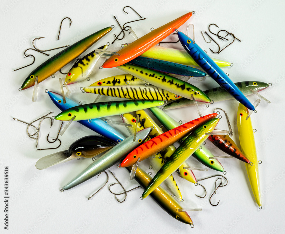 A pile of beautiful deep sea fishing lures with hooks scattered around on a  white background Stock Photo