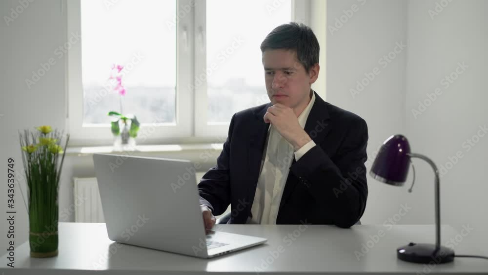 Young man working at laptop computer in office. Businessman or manager job Young man working at laptop computer in office. Businessman or manager job