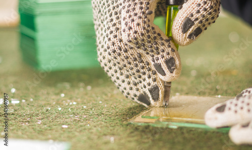 Closeup hand wearing white working glove using handheld cutting engravement tool for glass