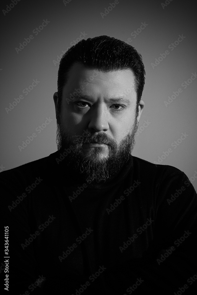 Black and white studio portrait of brutal bearded man in turtleneck