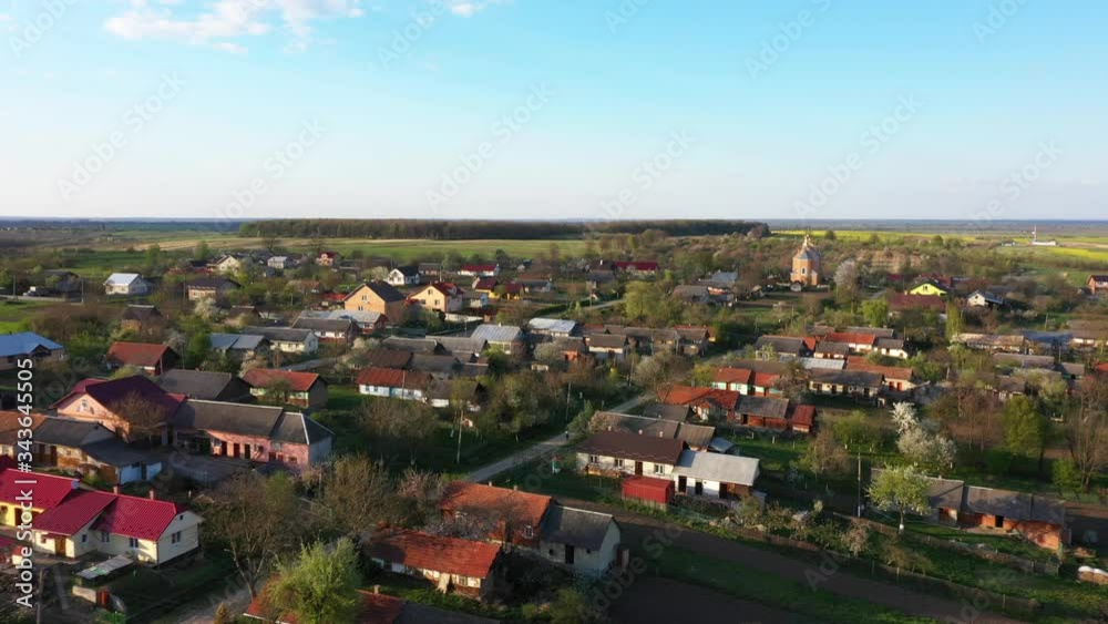 Aerial drone flyover above of traditional village. Huts with red roofs among green trees, blue sky on background Aerial drone flyover above of traditional village. Huts with red roofs among green trees, blue sky on background