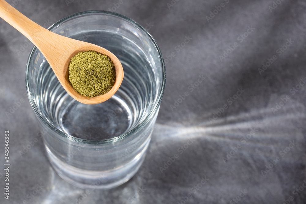 Moringa oleifera - Spoon with organic moringa and glass of filtered water Moringa oleifera - Spoon with organic moringa and glass of filtered water