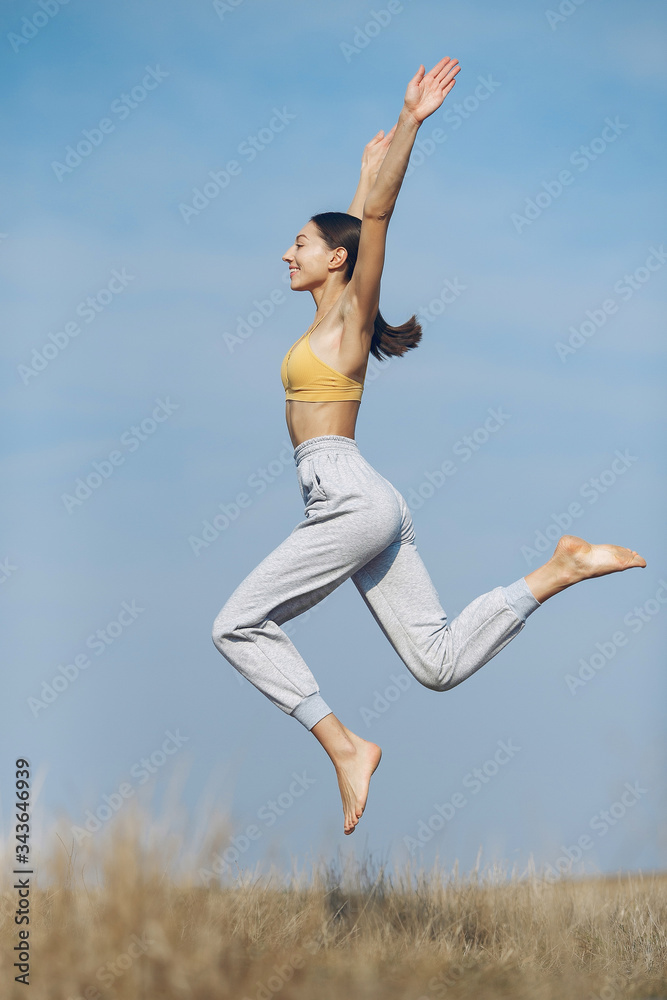 Beautiful girl training on a sky background. Woman in a yellow top. Lady make a yoga Beautiful girl training on a sky background. Woman in a yellow top. Lady make a yoga