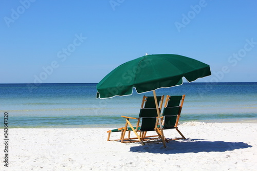 Two chairs and green umbrella on white sand beach