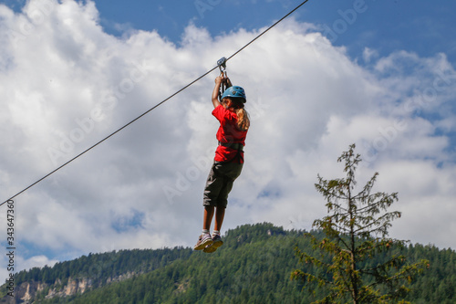 little girl sliding on a zipline in an adventure park. Young girl playing and having fun doing activities outdoors. Happiness and happy childhood concept