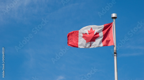 Canadian flag pole on blue sky with copy space background. Canada flag country maple leaf symbol and nationalism concept