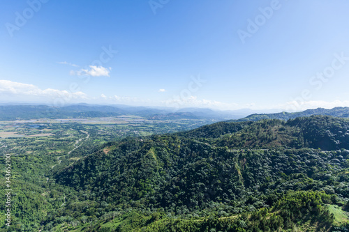 Mountain view from above on green mountains hills meadows and blue sky. Green landscape aerial drone view on the forest 