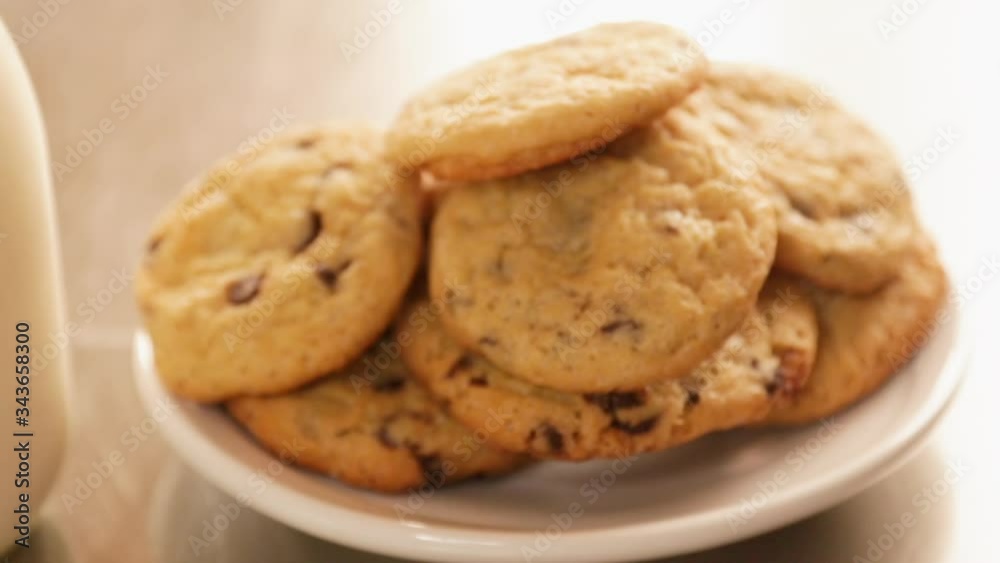 Close-up homemade chocolate chip cookies with a glass of milk on the kitchen table - children's snack - cookies with a glass of milk with a window behind in the afternoon Close-up homemade chocolate chip cookies with a glass of milk on the kitchen table - children's snack - cookies with a glass of milk with a window behind in the afternoon