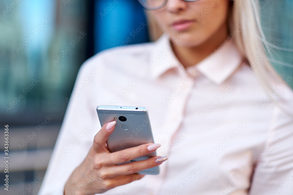 Business woman using smart phone on a background office building. Business woman using smart phone on a background office building.
