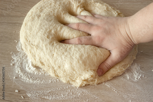 Top view on the hands of a cook who kneads yeast dough for baking