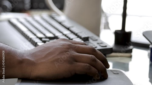close up shot of an African American male hand using a computer mouse and keyboard to search for jobs and work from home due to the global pandemic Covid-19 virus outbreak across the country.