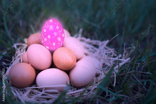 There are many eggs that are stacked together and have pink eggs is decorated with colorful colors are floral patterns put on top of the green grass background. Happy Easter day concept