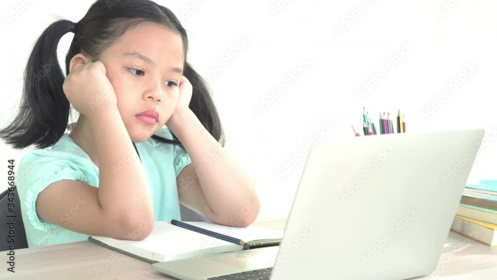 Asian kid schoolgirl studying homework math during her online with laptop lesson at home, social distance during quarantine, self-isolation, online education digital technology concept, home schooler. Asian kid schoolgirl studying homework math during her online with laptop lesson at home, social distance during quarantine, self-isolation, online education digital technology concept, home schooler.