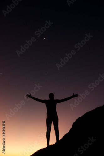 silhoutte of a man in nature with the moon in the sky
