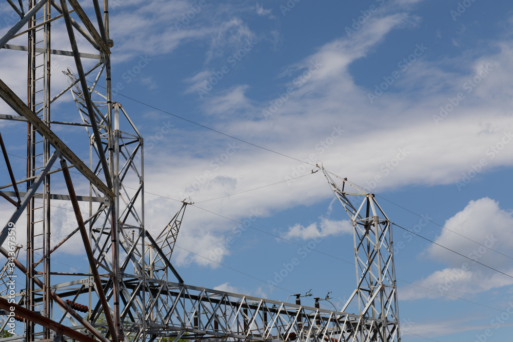 Electrical power substation metal structures and wires, power transfer station against a blue sky with clouds, horizontal aspect Electrical power substation metal structures and wires, power transfer station against a blue sky with clouds, horizontal aspect