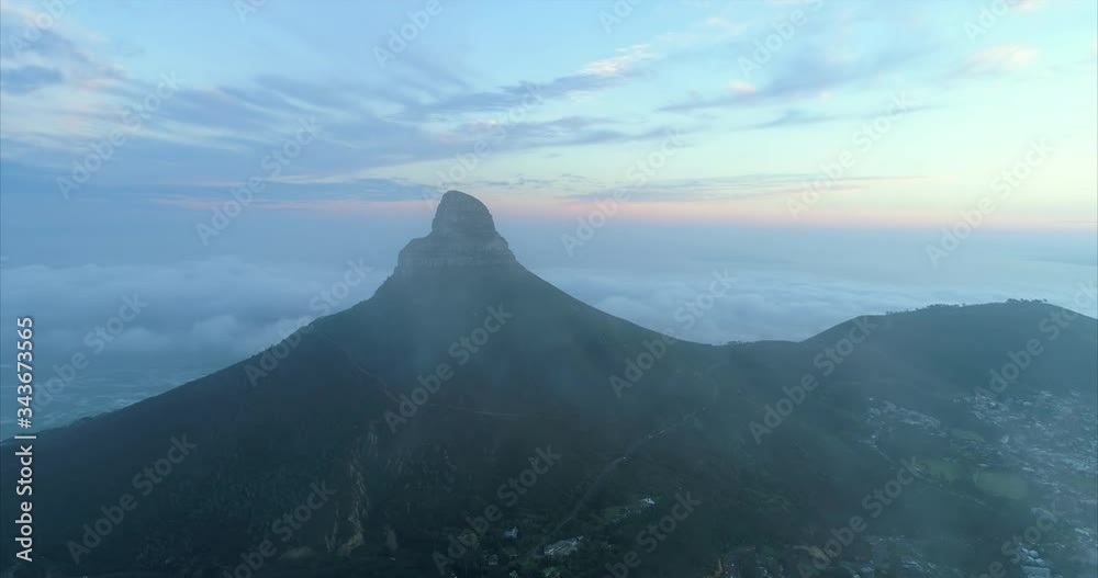 Aerial shot of an amazing mountain peak over a scenic town at dusk, drone flying forward towards the mountain through the clouds - Cape Town, South Africa