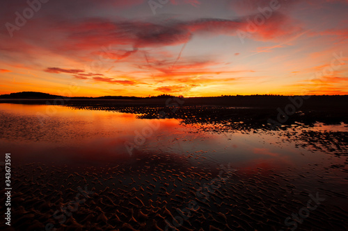 Vibrant reflection of sky at sunset over beach