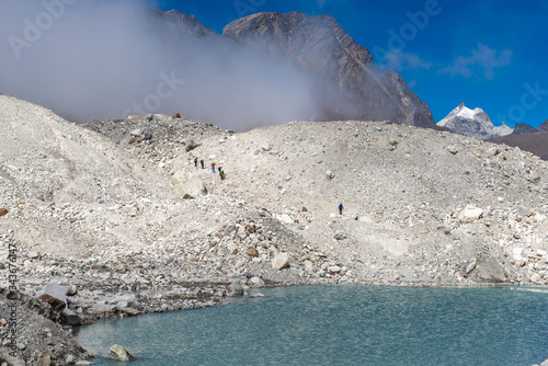 Group of trekker walking on Ngozumpa glacier the longest glacier in the Himalayas below the sixth highest mountain in the world Cho Oyu. photo