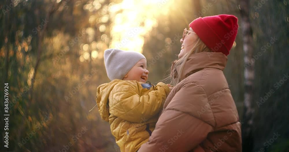 Slow motion: Happy family mom with her son play in the park at sunset. The concept of family values. Active lifestyle. A woman walks with a child in a winter park. The boy spends time with his mother. Slow motion: Happy family mom with her son play in the park at sunset. The concept of family values. Active lifestyle. A woman walks with a child in a winter park. The boy spends time with his mother.
