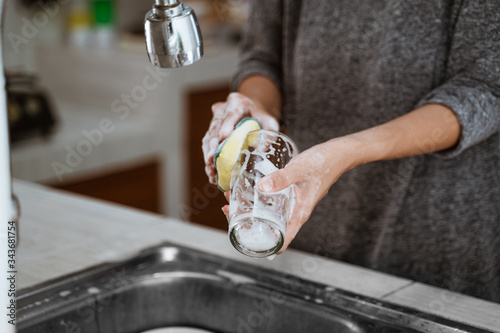 Cropped image of a woman is washing dishes while doing cleaning at home