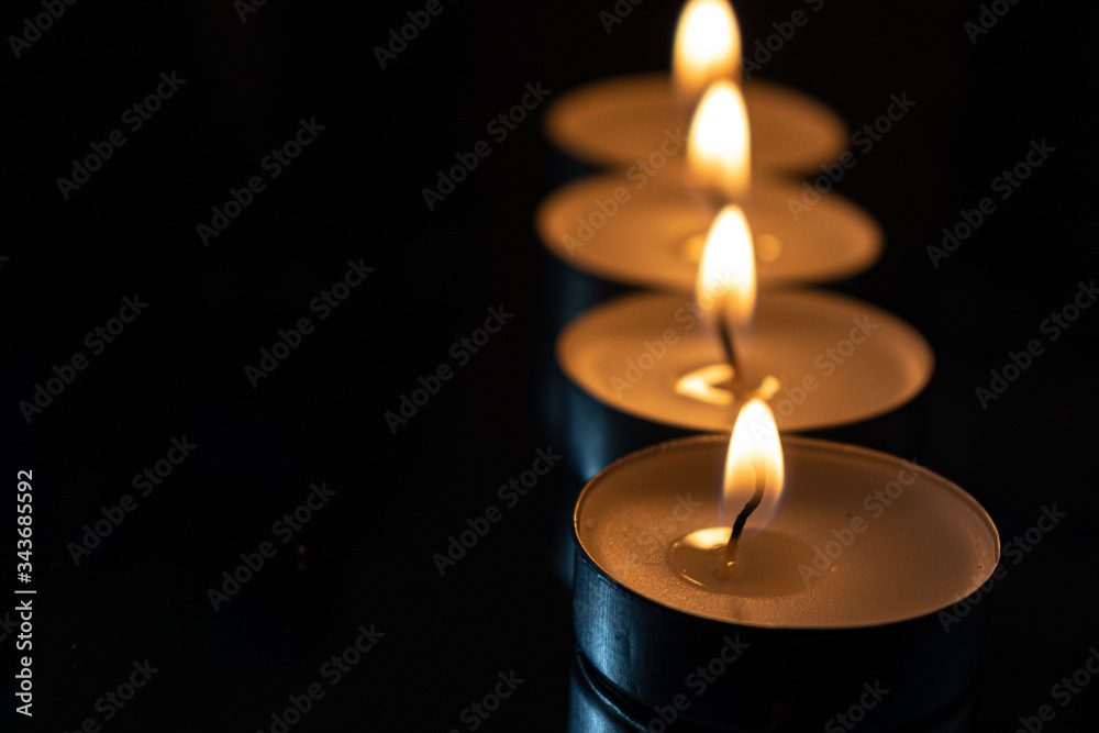 four candles lined up with dark background showing the light of the fire and the reflection in the mirror four candles lined up with dark background showing the light of the fire and the reflection in the mirror