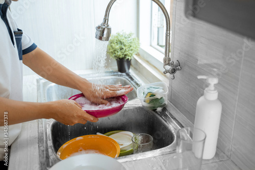 close up of washes dishes with a sponge in the sink