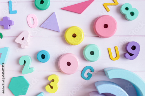 Wooden toy rainbow, numbers, blocks, pastel color arc on pink background. Natural no plastic toys for creativity development. Flat lay, top view. Educational games for kindergarten, preschool kids