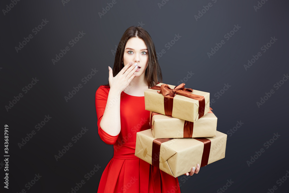 Surprised girl with balloons and a gift. A teenager girl in a red dress opened her mouth in surprise, holding balloons and a gift box in her hands. Surprised girl with balloons and a gift. A teenager girl in a red dress opened her mouth in surprise, holding balloons and a gift box in her hands.