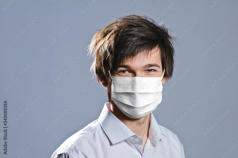 portrait of handsome young man on grey background. man wearing protective mask against infectious diseases and flu. Health care concept. portrait of handsome young man on grey background. man wearing protective mask against infectious diseases and flu. Health care concept.