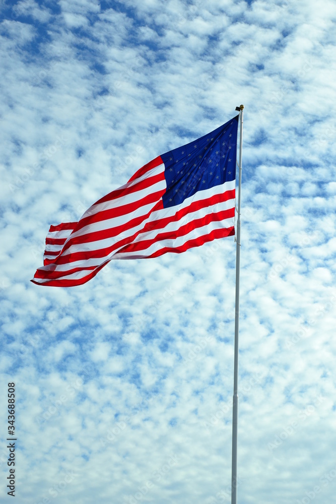 Obraz premium American flag flying in wind, beautiful clouds pattern background.