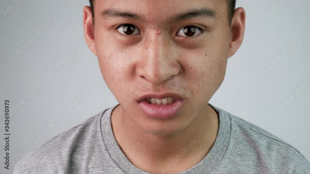Asian teenage guy in grey t-shirt excited and happy with what he saw in front.