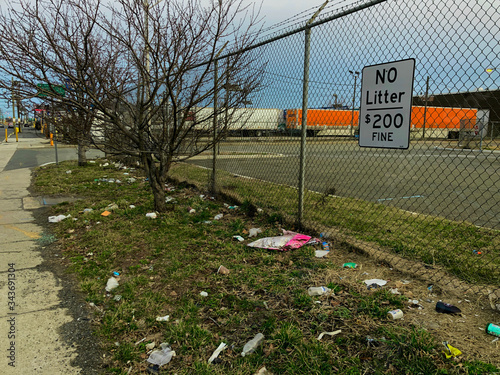 Trash litters the fence along side road in Elizabeth New Jersey where sign posted states “No Litter $200 Fine”