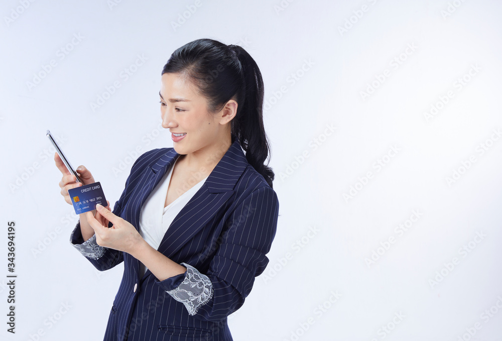 asian woman using credit card and mobile phone. isolated over white background asian woman using credit card and mobile phone. isolated over white background