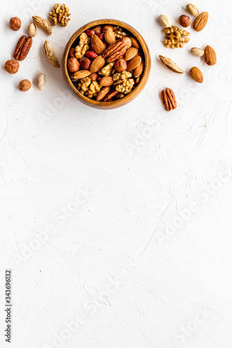 Mixed nuts in bowl on white background top-down frame copy space
