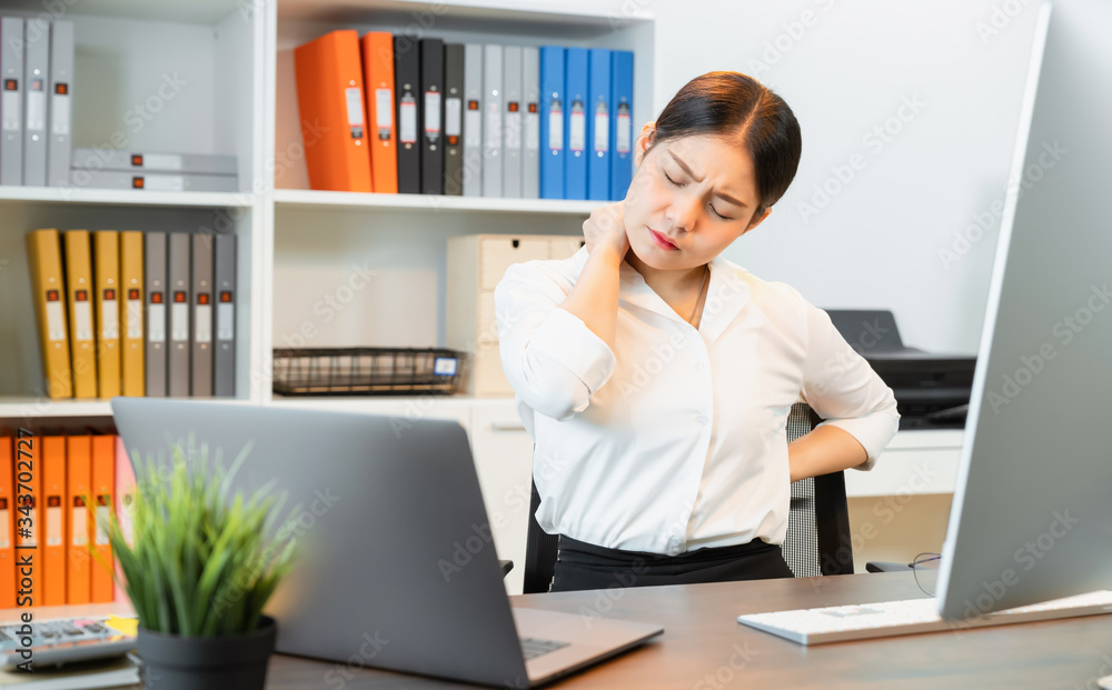 Asian business woman have a backache because sitting and working with using a computer for a long time. This may be the cause of office syndrome. Asian business woman have a backache because sitting and working with using a computer for a long time. This may be the cause of office syndrome.