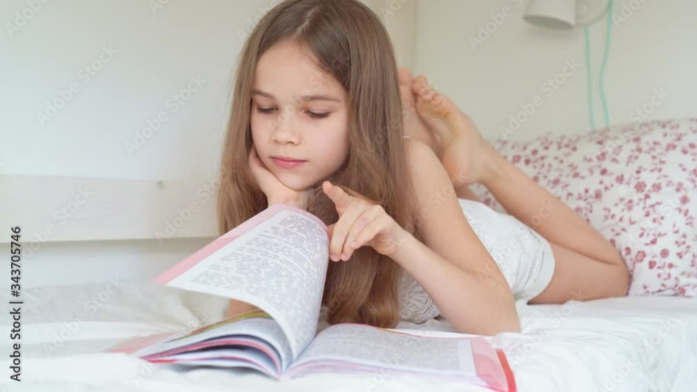 school concept. little girl with book lying on bed school concept. little girl with book lying on bed