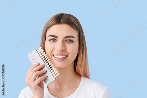 Beautiful young woman with teeth samples on color background