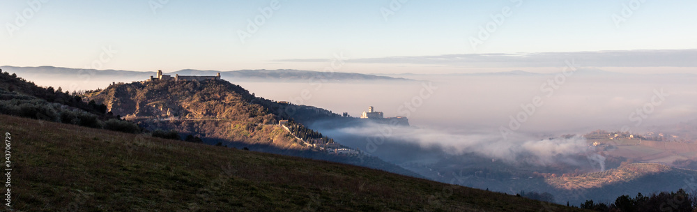 A panoramic, epic view of St.Francis church in Assisi town (Umbria) above a sea of fog at dawn