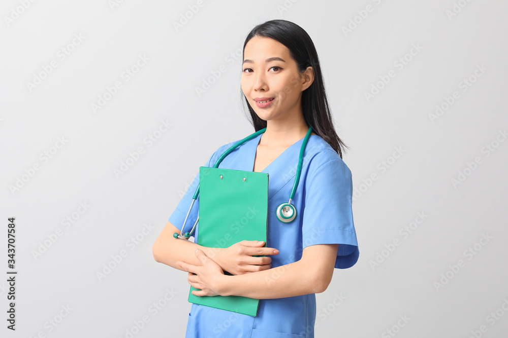 Female Asian doctor with clipboard on light background Female Asian doctor with clipboard on light background