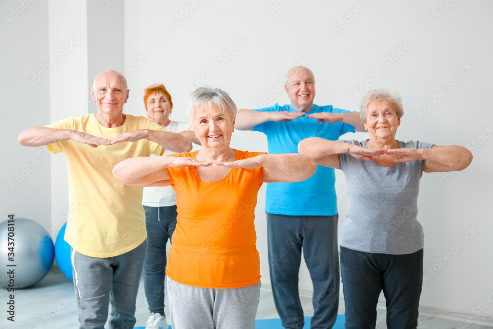 Fototapeta premium Elderly people exercising in gym