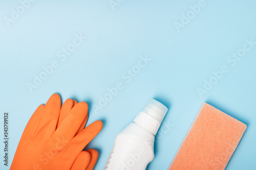 sponge, gloves and detergent on blue background, copy space