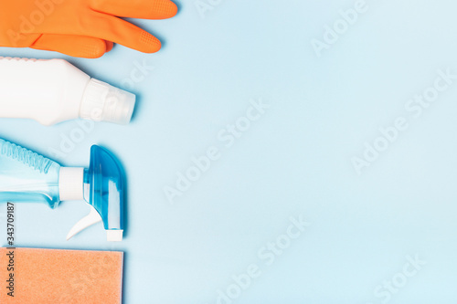 Orange gloves and spray bottle on blue background copy space, Cleaning concept.