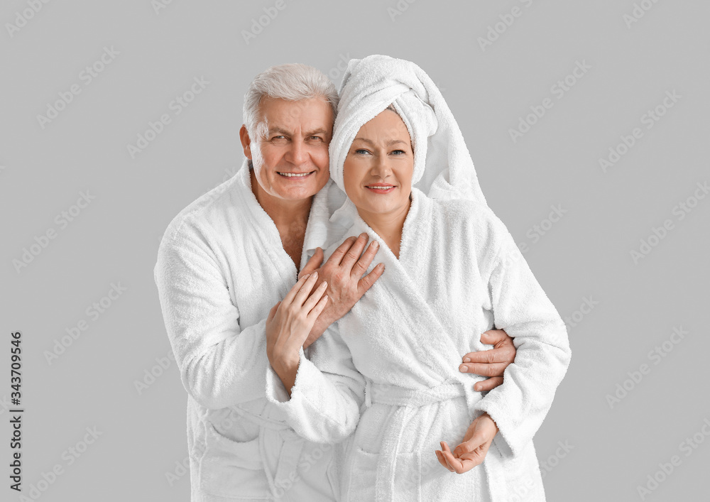 Mature couple in bathrobes on grey background Mature couple in bathrobes on grey background