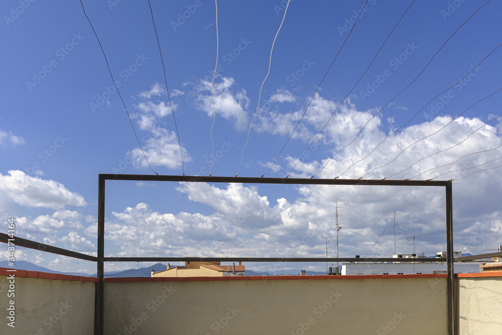Sunny blue sky with some clouds on a clothesline on a roof building with nobody on it Sunny blue sky with some clouds on a clothesline on a roof building with nobody on it