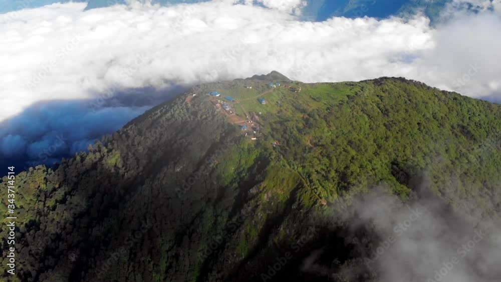 Beautiful aerial shot of going away from Pathivara Devi Goddess, a holy hindu shrine on top of a green hill. Drone Shot. Taplejung, East Nepal. Over the clouds, High Altitude, Spring Time. Beautiful aerial shot of going away from Pathivara Devi Goddess, a holy hindu shrine on top of a green hill. Drone Shot. Taplejung, East Nepal. Over the clouds, High Altitude, Spring Time.