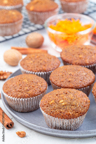 Homemade carrot cake muffins with walnuts on gray plate, vertical