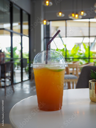 cold iced tea with lemon and straw in takeaway plastic cup.